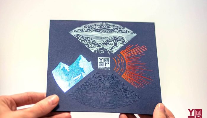 Cartes de vœux rouge et bleue avec motifs de feu d’artifice en dorure chaude, présentées dans un atelier d’impression. avec du gaufrage et de la dorure