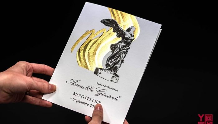 Carte de vœux blanche avec statue en noir et flamme dorée, destinée à une institution officielle.